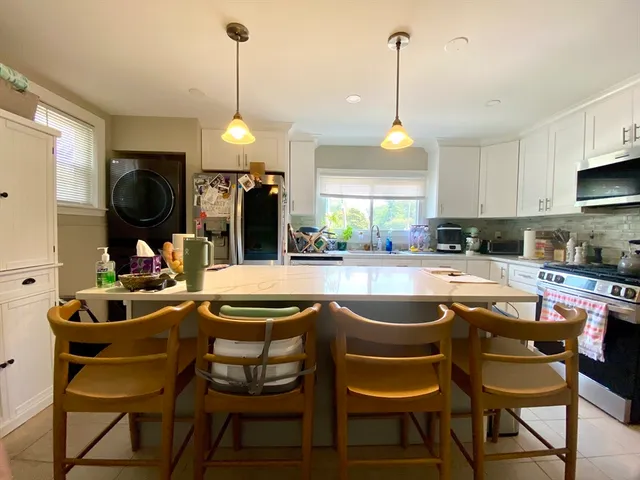 a kitchen island with stainless steel appliances granite countertop a stove a sink and a dining table with kitchen island