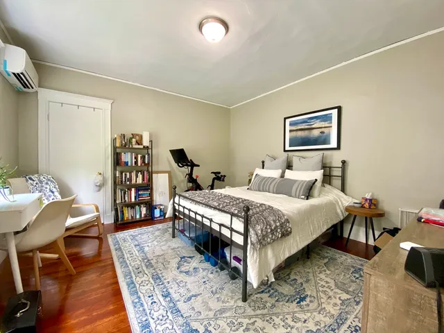 a bedroom with a bed a table and wooden floor