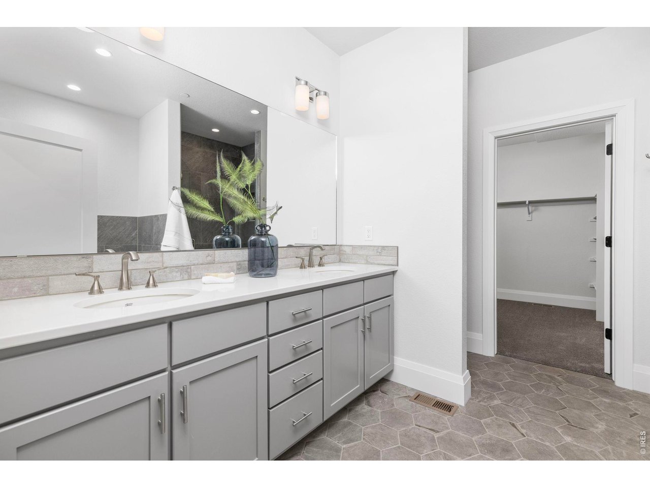 5700 West 2nd Street Road Greeley, CO 80634 - Photo 19 of 40 The primary ensuite bath, featuring dual vanities, a full-width mirror, porcelain tile flooring, and porcelain vanity sinks