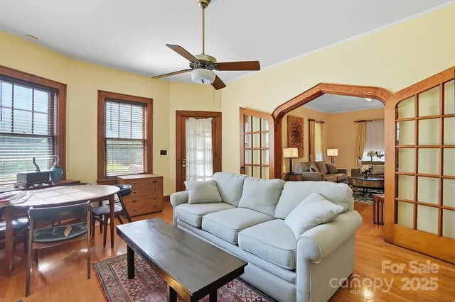 a living room with furniture a large window and wooden floor