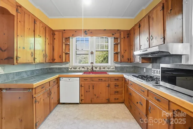 a large kitchen with stainless steel appliances granite countertop a sink counter space cabinets and a large window