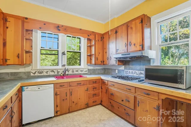 a kitchen with stainless steel appliances granite countertop a sink a stove and cabinets