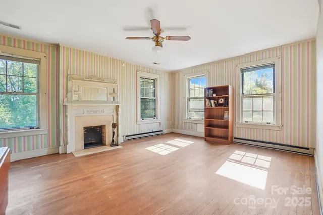 a view of an empty room with a window and a kitchen
