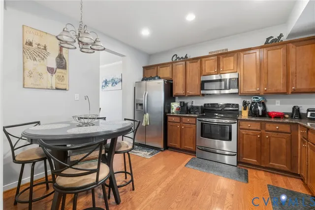 a kitchen with stainless steel appliances kitchen island granite countertop a dining table chairs and refrigerator