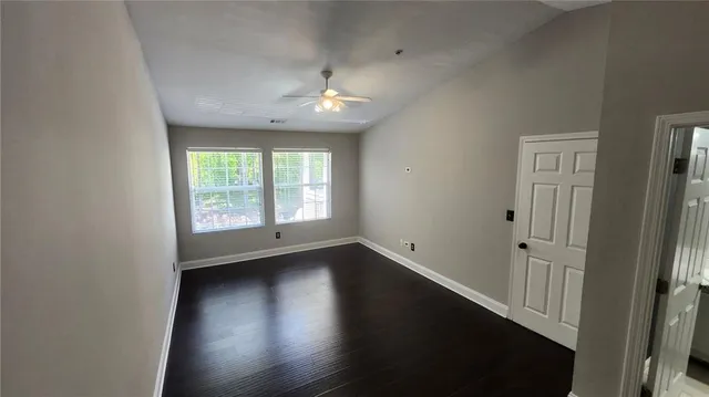 an empty room with wooden floor and windows
