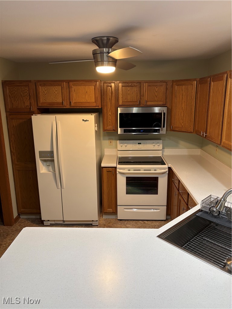 6695 Clingan Road, Unit 24 Youngstown, OH 44514 - Photo 4 of 26 Kitchen featuring white appliances, light countertops, brown cabinetry, and a ceiling fan