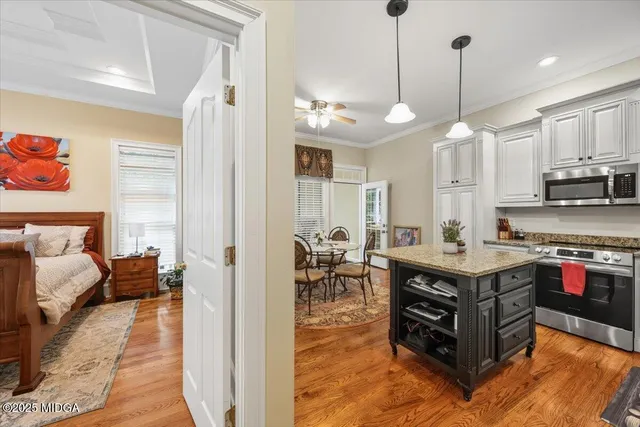 a open kitchen with stainless steel appliances granite countertop a stove top oven a dining table and chairs with wooden floor