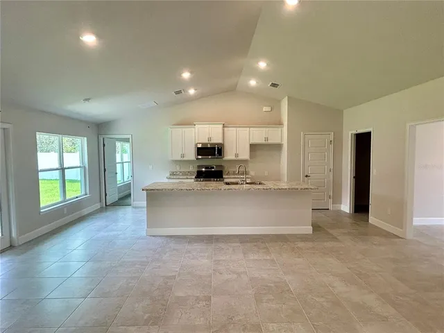 a large kitchen with stainless steel appliances kitchen island granite countertop a large counter top and a stove top oven