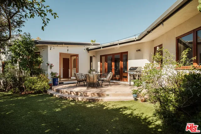 a patio with table and chairs and potted plants