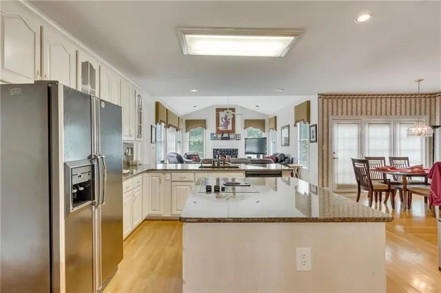 a kitchen with stainless steel appliances granite countertop a refrigerator a stove and a dining table with wooden floor