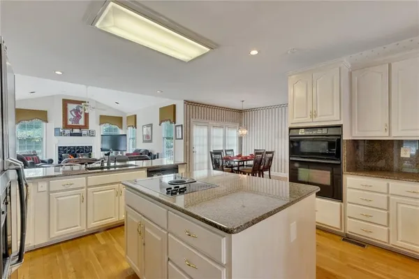 a kitchen with stainless steel appliances a sink dishwasher stove refrigerator and microwave with wooden floor