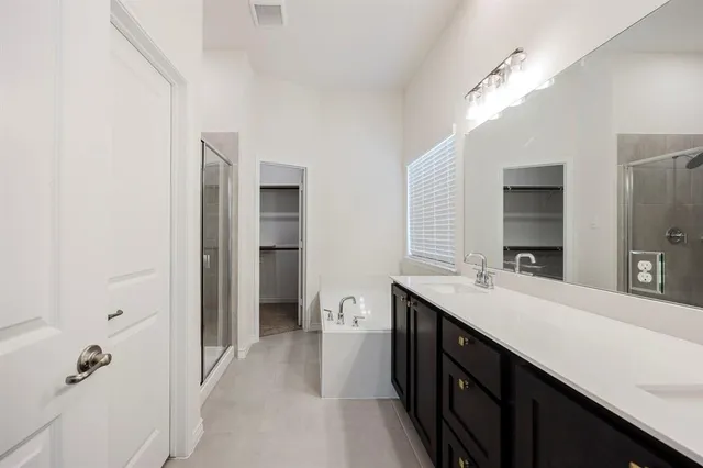 a spacious bathroom with a double vanity sink a mirror and a shower