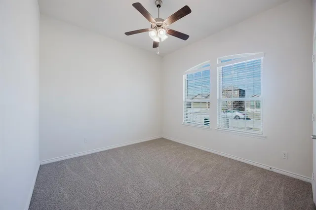 an empty room with windows and fan