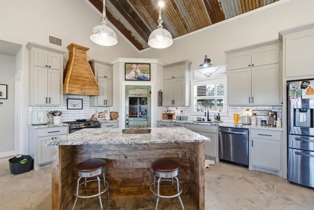 a kitchen with kitchen island granite countertop a sink cabinets stainless steel appliances and a counter top space