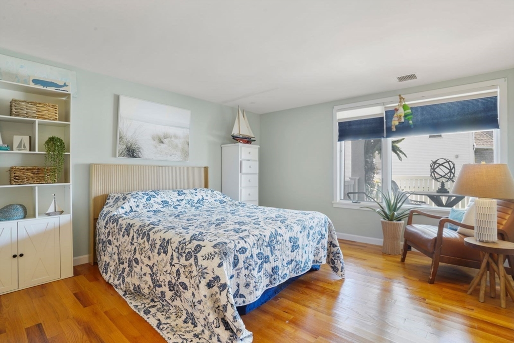 1 Commodore Court, Unit 104 Hull, MA 02045 - Photo 19 of 35 a bedroom with a bed a table and painting on the wall