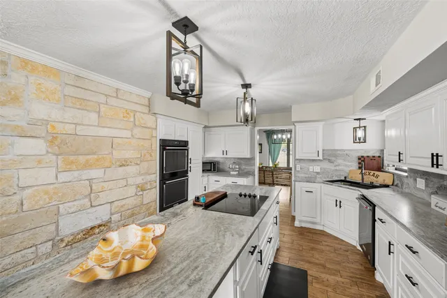a kitchen with granite countertop a sink a counter space appliances and cabinets