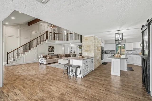 a large white kitchen with wooden floor and stainless steel appliances