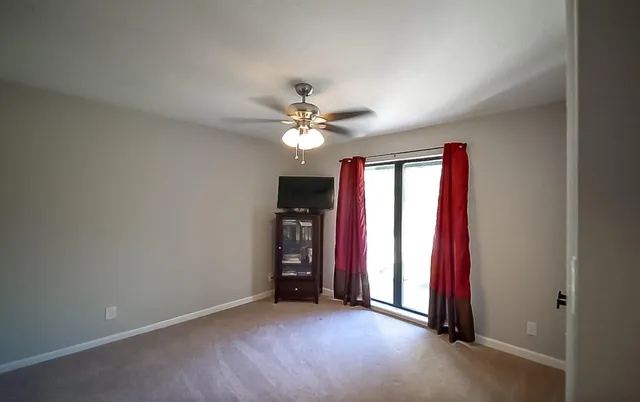 an empty room with chandelier fan and windows