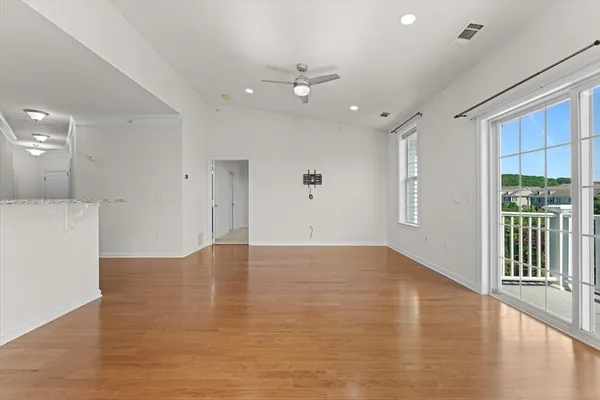 a view of an empty room with wooden floor and a window