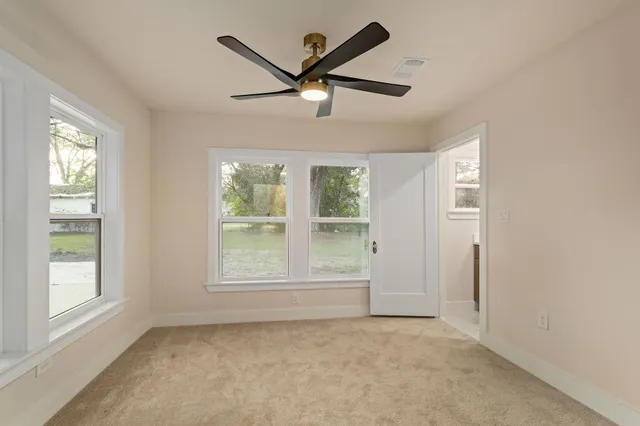an empty room with wooden floor closet and windows