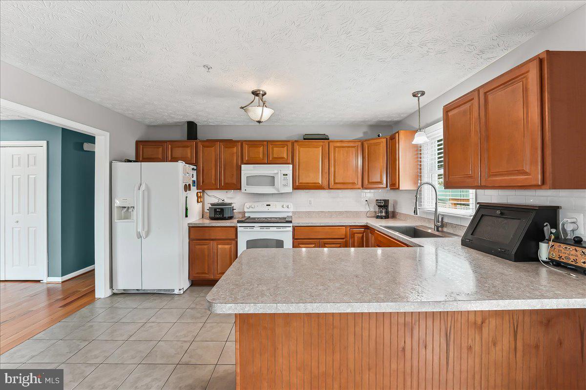 107 Britton Drive Rising Sun, MD 21911 - Photo 15 of 30 a kitchen with stainless steel appliances granite countertop a refrigerator a sink dishwasher a stove with wooden cabinets and floor