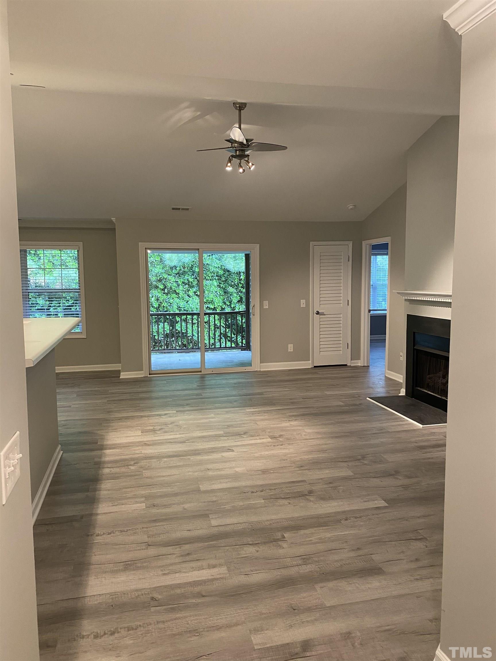 an empty room with wooden floor fireplace and windows