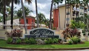 a front view of multi story residential apartment building with yard and sign board
