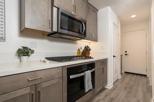 a kitchen with stainless steel appliances a stove a microwave oven cabinets and a wooden floor