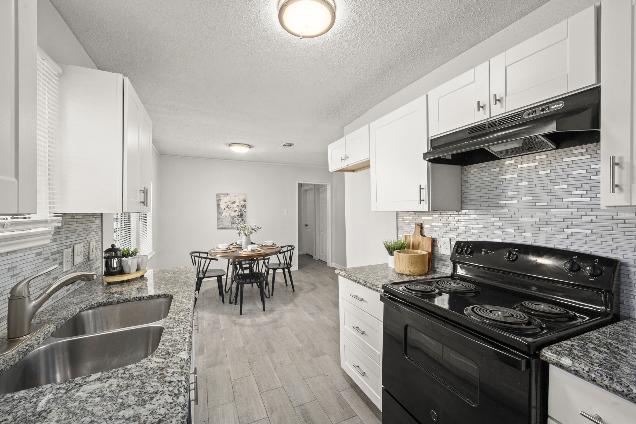 5219 Myrtlewood Street Houston, TX 77033 - Photo 17 of 36 a kitchen with granite countertop a stove top oven a sink dishwasher a dining table and chairs with wooden floor