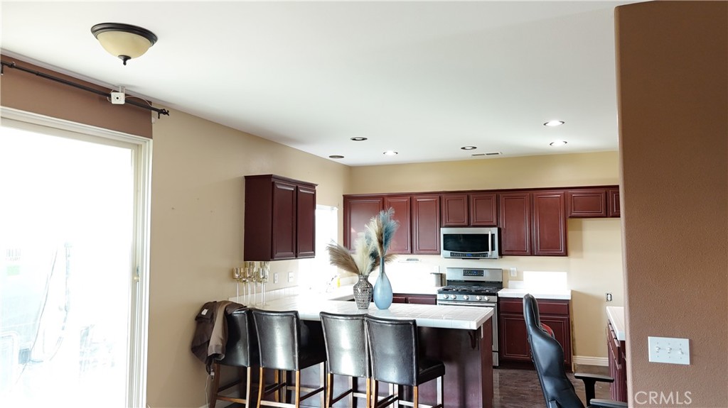 176 Nightfall Road San Jacinto, CA 92582 - Photo 4 of 11 a kitchen with stainless steel appliances kitchen island granite countertop a refrigerator a stove a sink and a microwave