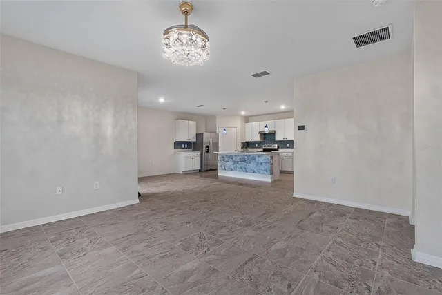 an empty room with windows and chandelier fan