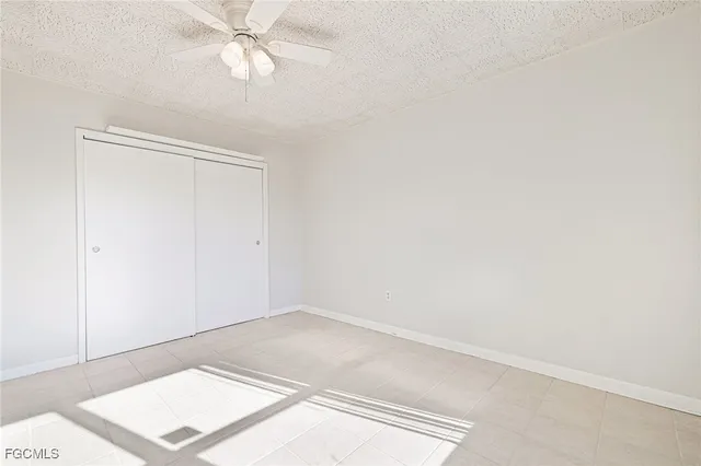 a view of an empty room with window and a chandelier fan