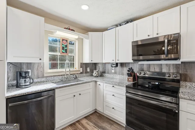 a kitchen with cabinets appliances a sink and a window