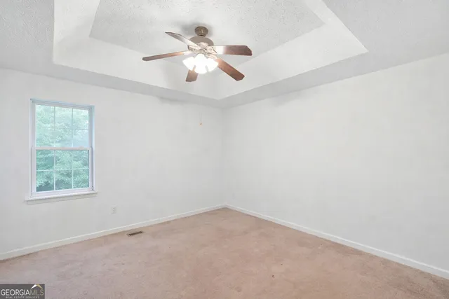 an empty room with windows and fan