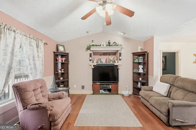 a living room with furniture a flat screen tv and a window