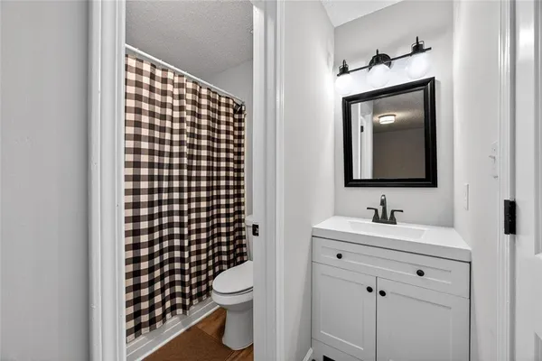 a bathroom with a toilet sink vanity and mirror