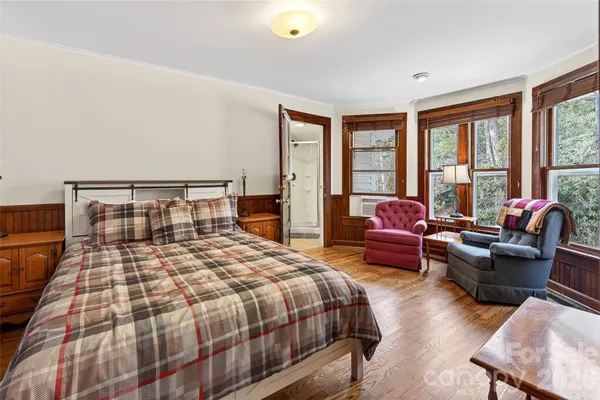 a bedroom with a bed couch and windows