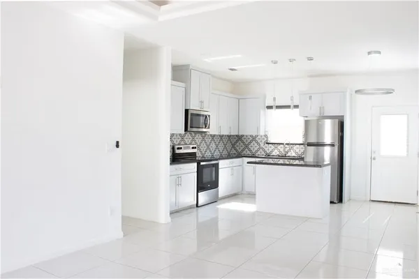 a large kitchen with a refrigerator and white cabinets