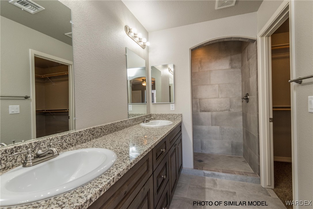 3369 North Bryce Road Golden Valley, AZ 86413 - Photo 8 of 12 a bathroom with a granite countertop sink a mirror and a shower