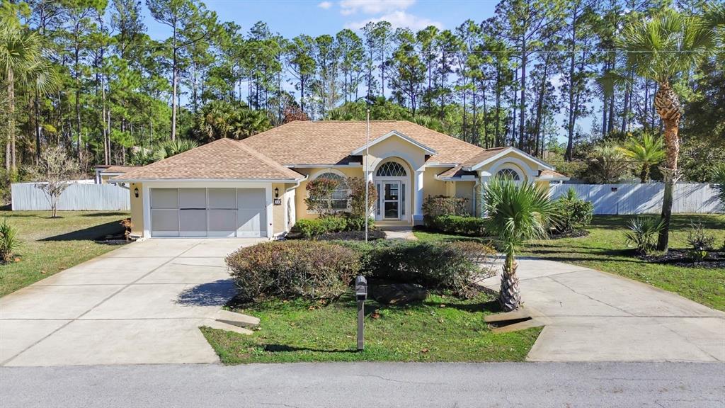 24 Regency Drive Palm Coast, FL 32164 - Photo 34 of 36 a front view of a house with a garden and trees