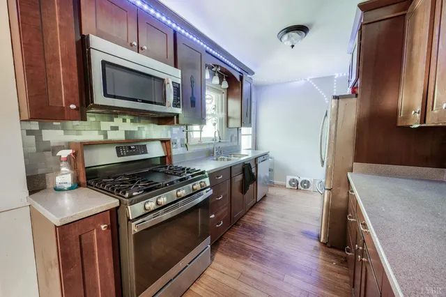 a kitchen with stainless steel appliances granite countertop a stove a sink and a microwave