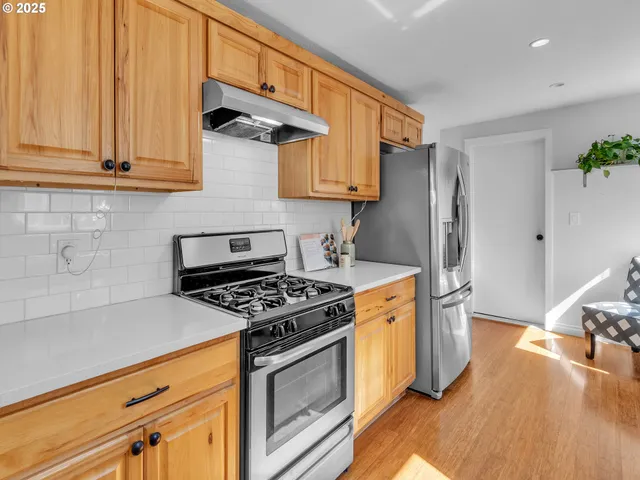 a kitchen with stainless steel appliances granite countertop a stove a refrigerator and a white cabinets