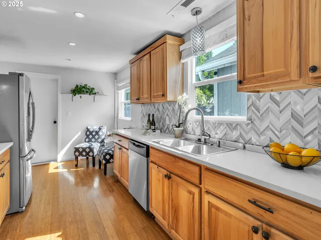 a kitchen with stainless steel appliances granite countertop a sink dishwasher stove and wooden cabinets with wooden floor