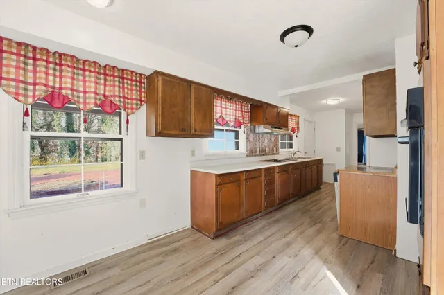 a kitchen with stainless steel appliances kitchen island wooden cabinets a window and a sink