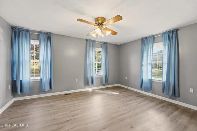 a view of an empty room with window and wooden floor