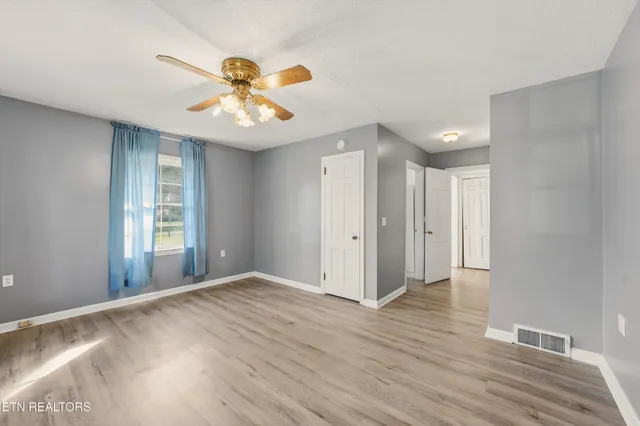 a view of an empty room with window and wooden floor
