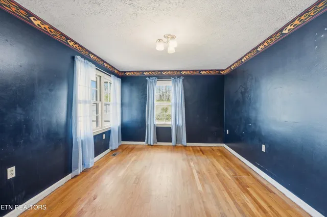 a view of a big room with wooden floor and windows