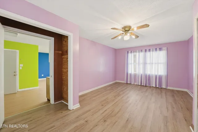 a view of an empty room with window and wooden floor