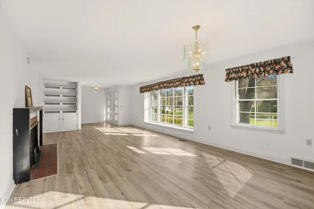 a view of empty room with wooden floor and windows