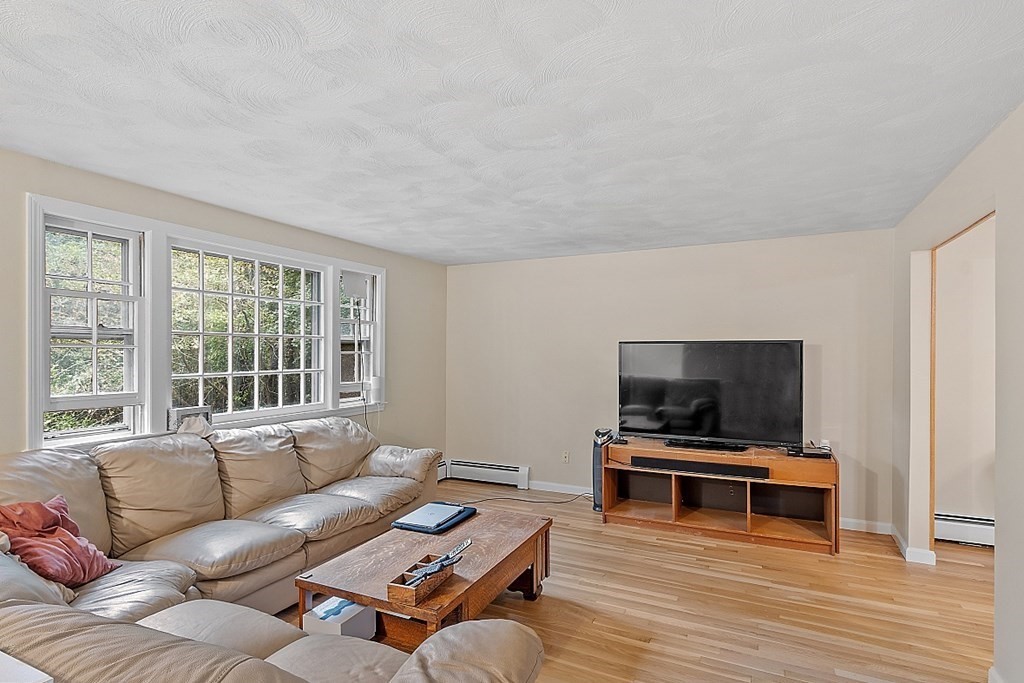 77 Hunt Road Chelmsford, MA 01824 - Photo 2 of 36 a living room with furniture and a flat screen tv with wooden floor